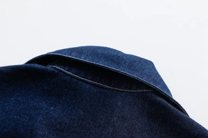 Close-up of neat stitching and twill texture on a dark blue denim jacket neckline