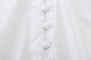 Detailed view of the pure white cotton shirt featuring elegant fabric-covered buttons