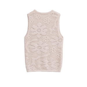 Détail d'un gilet en maille rose pâle avec des motifs floraux en relief et une encolure ronde