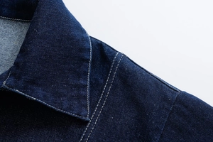 Detail of classic pointed collar and contrast stitching on dark blue denim jacket