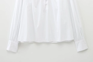 Detail of white cotton blouse showing covered buttons and pleated cuffs with button straps