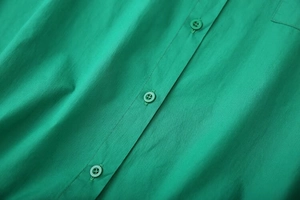 Detailed macro view of the emerald green cotton fabric shirt and matching resin buttons