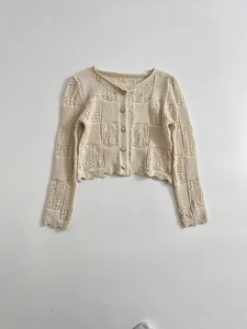 Détail d'un cardigan en maille crochetée ajourée avec bords festonnés et boutons