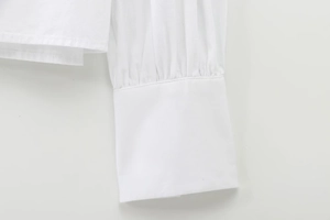 Detail view of white cotton shirt cuffs featuring elegant pleated design and fine stitching