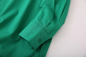 Close-up of emerald green long-sleeved shirt cuff with matching round resin button detail