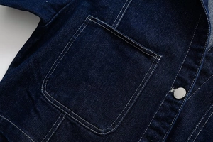 Detail of dark blue denim jacket with contrast stitching and silver fashion jeans button