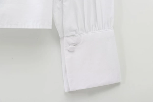 Detail of white cotton shirt cuff with pleats and a matching fabric-covered button