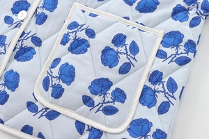 Detail of diamond quilted light blue fabric featuring dark blue rose floral print and pocket