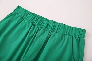 Detail of bright green trousers showing the elastic waist and side pockets construction