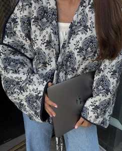Dettaglio della giacca trapuntata con motivo paisley blu e finiture in piping nero