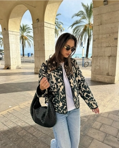 Détail d'une veste chic à imprimé léopard avec un sac à main en cuir tressé
