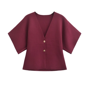 Close-up of wine red knit cardigan featuring oversized sleeves and marble pattern buttons
