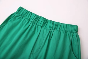 Detail of green trousers featuring an elastic waistband and functional side pockets