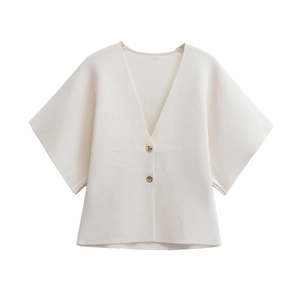 Close-up of cream knit V-neck cardigan featuring textured fabric and amber-tone buttons