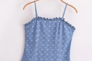 Detail of light blue denim top with ruffle neckline and white floral print on hanger
