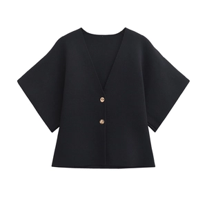 Detail of V-neck knitted cardigan with black fabric and decorative gold buttons
