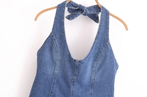 Détail d'un haut licou en denim bleu avec un décolleté en V et une fermeture à nœud