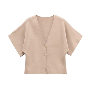 Detail of light brown knit cardigan showing the soft fabric texture and button closure