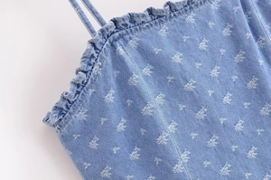 Detailed view of blue denim dress with ruffle neckline and distressed pattern