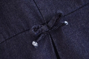 Gros plan sur le tissu denim bleu foncé avec un nœud décoratif et une texture en sergé