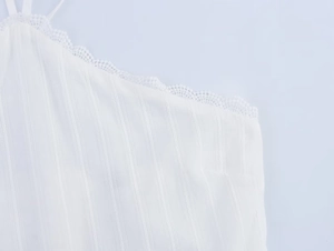 Close-up of white halter top featuring vertical stripe texture and delicate crochet lace trim