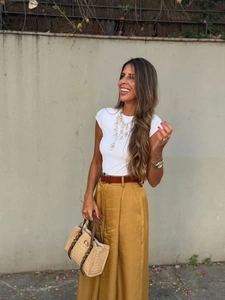 Détail du pantalon large jaune à taille haute avec t-shirt blanc et sac cabas en paille