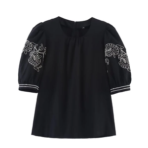 Close-up of intricate white floral embroidery and double stripes on black puff sleeves