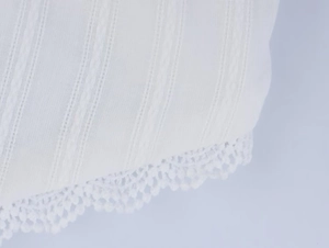Detail of white striped fabric and delicate crochet lace trim on summer halter top