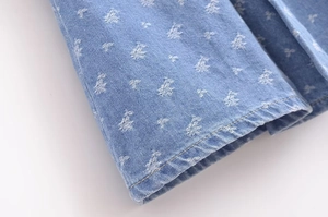 Detail of light blue denim fabric with floral pattern and neat brown twin-needle stitching
