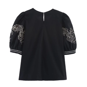 Detail of puff sleeves with white floral embroidery and striped cuffs on black top