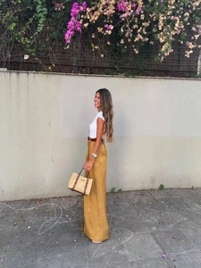 Détail du pantalon large en satin doré à taille haute avec une ceinture en cuir marron
