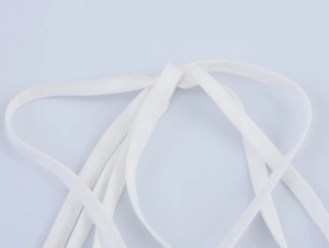 Detailed close-up of white fabric strap knot with fine stitching on a summer dress