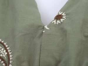 Detailansicht aus grünem Baumwollleinen mit floraler Gänseblümchen-Stickerei und Blattmustern