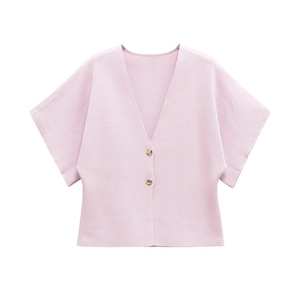 Detail of light pink knit cardigan featuring V-neck and decorative gold metal buttons