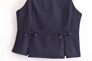 Détail du haut en jean bleu marine avec nœuds à la taille et ourlet plissé élégant