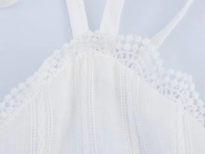 Detail of white halter dress featuring delicate crochet lace trim and textured fabric