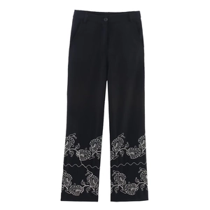 Detailed embroidery on black straight-leg trousers with white floral pattern on the hem