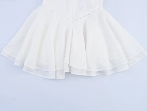 Detail of white pleated dress hem featuring delicate double-layer lace trim and vertical texture