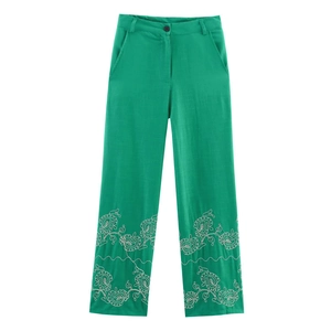 Detail of high-waisted green trousers with white floral embroidery at the leg cuffs