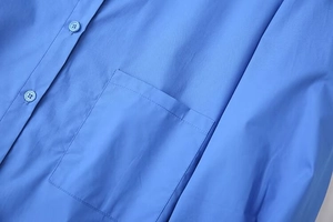 Close-up of blue shirt showing cotton fabric texture, square pocket and matching buttons