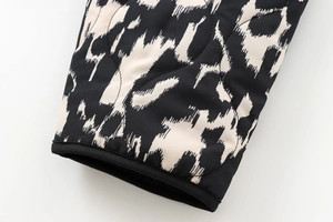 Détail de la manche d'une veste matelassée avec motif géométrique et bords noirs gansés