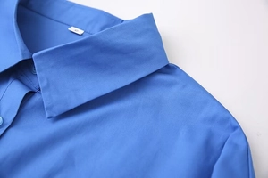 Detail view of bright blue shirt collar and shoulder stitching with size S label