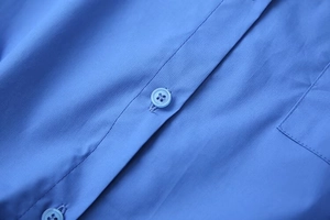 Detailed macro view of blue shirt front placket with matching buttons and pocket stitching