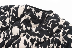 Détail de l'encolure ronde et matelassage ondulé sur une veste à imprimé noir et blanc