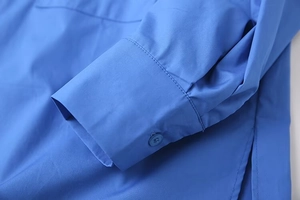 Detailed macro view of royal blue shirt sleeve with matching button and fine stitching