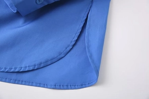 Detailed macro view of royal blue shirt featuring a curved hem and buttoned cuffs