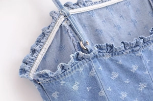 Detail of adjustable straps and floral ruffles on a light blue denim dress