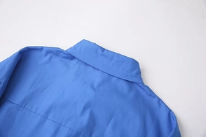 Detail view of the royal blue shirt collar and fine stitching on woven fabric