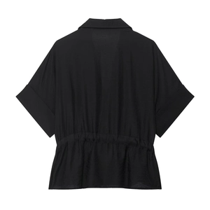 Détail d'une chemise noire à manches courtes avec taille élastiquée et ourlet plissé
