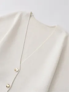 Close-up of a white knit cardigan featuring detailed texture and golden metallic buttons